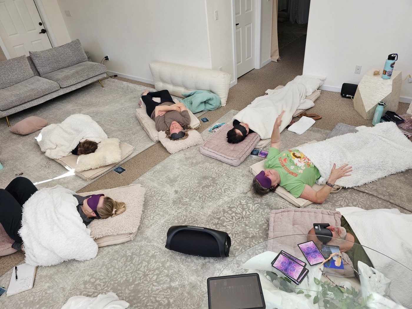 A group resting on the floor under blankets with eye masks on